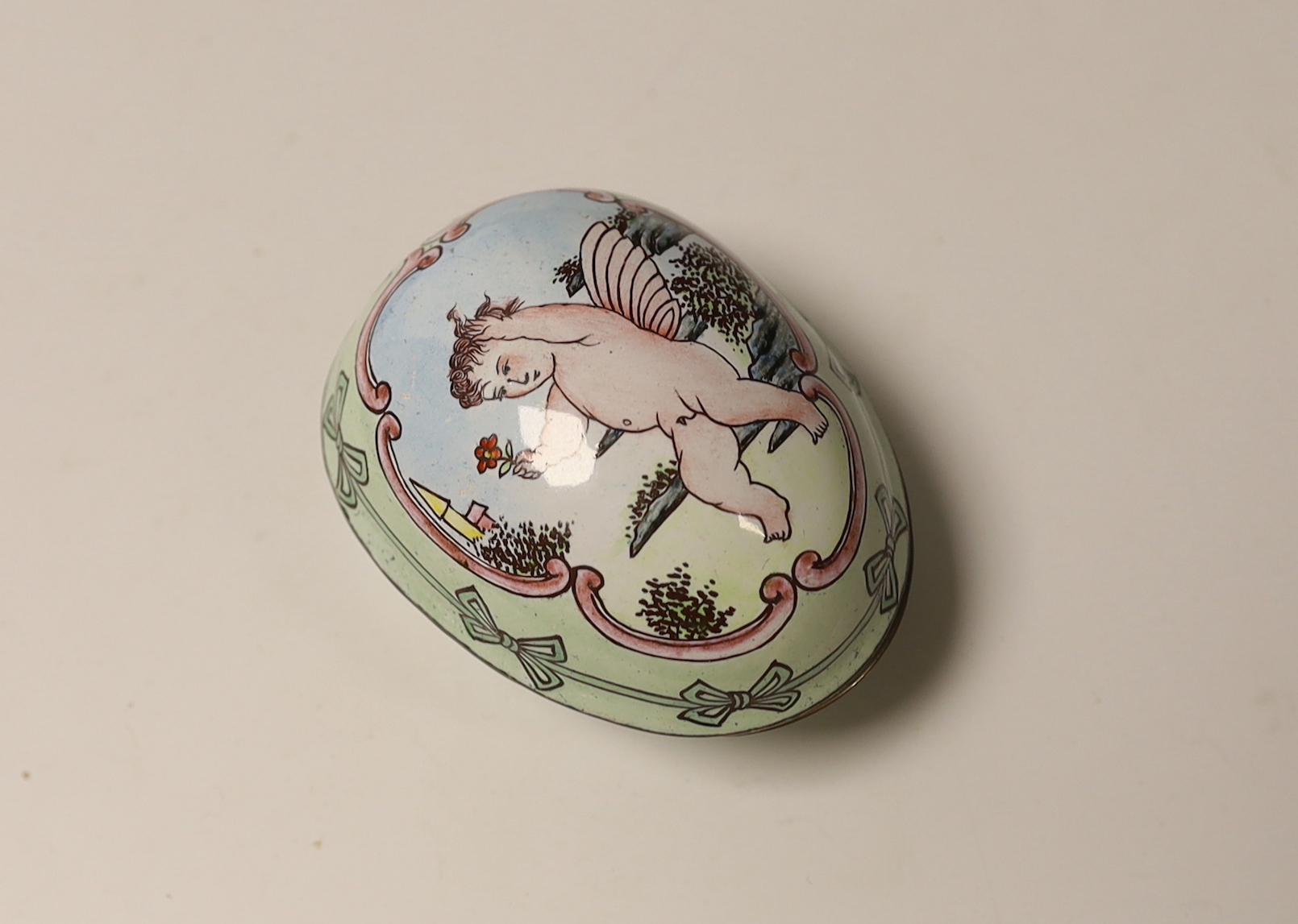 A silver plated and painted enamel egg shaped box and cover, opening to reveal a hinged pocket watch movement by Newsome & Co of London & Coventry, with painted dial, box 73mm.